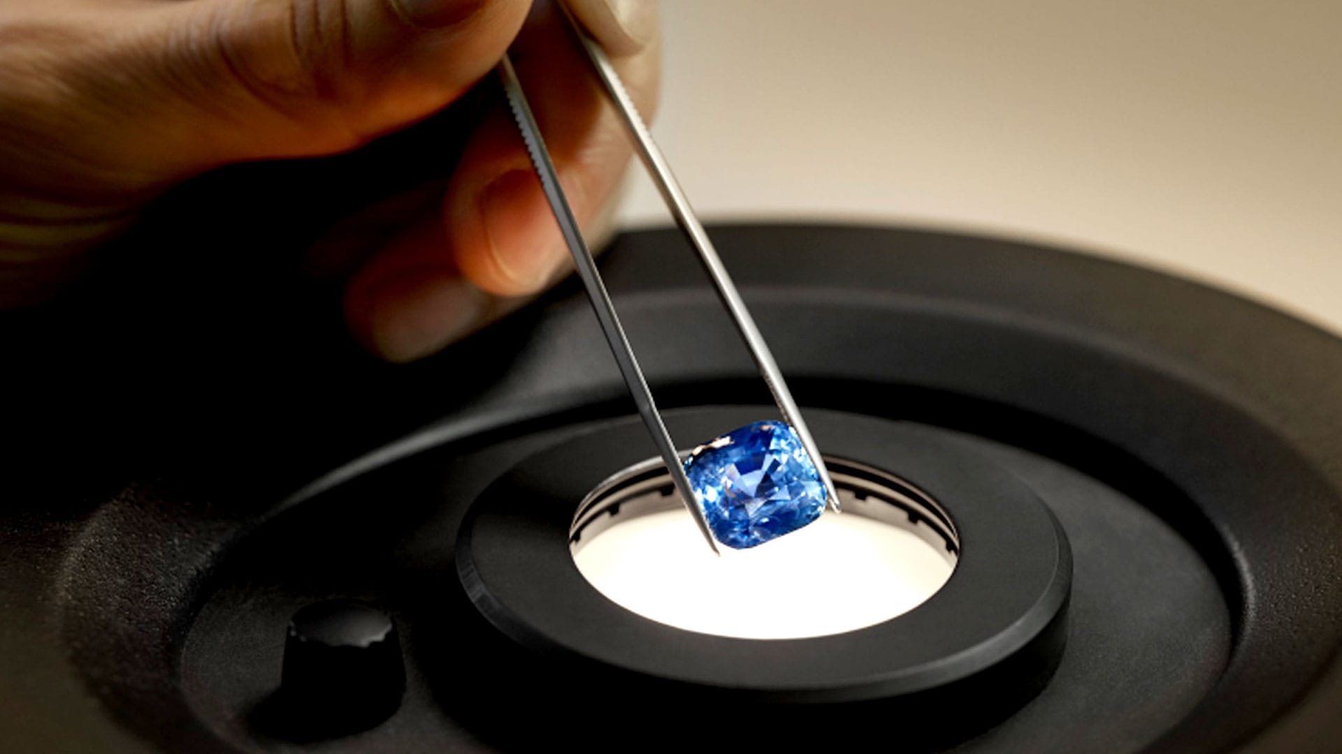 A person holds a sparkling blue sapphire delicately in their hand, showcasing its brilliance and unique color.