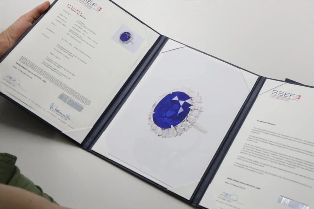 Gemstone Certification: A person holds a blue sapphire ring alongside gem certificates in a folder, showcasing the ring's authenticity and value.